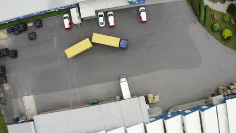Truck-with-trailer-leaving-logistics-factory-warehouse-parking-lot