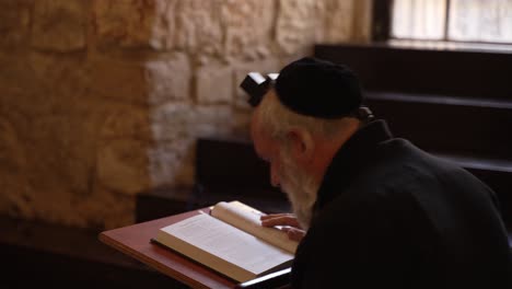 Religious-Jewish-man-praying-wearing-Tefillin,-phylacteries,-and-a-prayer-shawl-at-a-synagogue