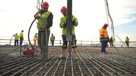 Construction-workers-pumping-concrete-into-metal-grid-foundations