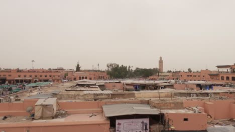 Panning,-high-angle-view-of-Jemaa-el-Fna-and-rooftops-in-Marrakesh,-Morocco