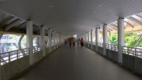 Perspective-view-of-people-walking-on-the-Skywalk-bridge-linked-between-BTS-Chong-Nonsi-station-and-Chong-Nonsi-Bridge-in-Bangkok,-Thailand