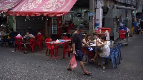 Point-of-view-of-people-walking-and-diners-dining-food-on-the-roadside-at-the-famous-Yaowarat-Chinatown,-Bangkok,-Thailand