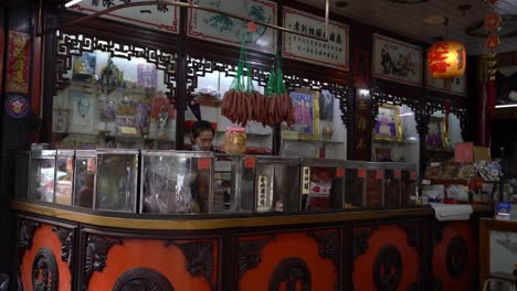 Point-of-view-of-a-lady-shopkeeper-busy-packing-and-preparing-dried-food-in-Yaowarat-Chinatown,-Bangkok,-Thailand