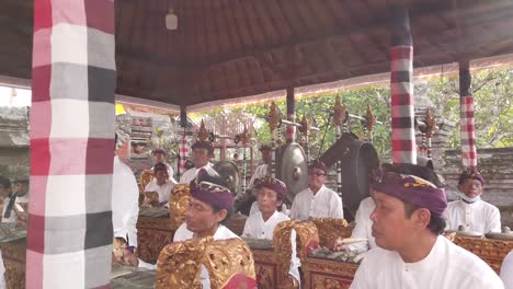 Musical-Ensemble-Play-Gamelan-Gong-Kebyar-Music-in-a-Hindu-Balinese-Temple-Ceremony-during-Daylight,-Hand-Held-Shot