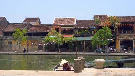 Fisherman-wearing-traditional-straw-hat-with-backdrop-of-Hoi-An-row-houses-in-Vietnam