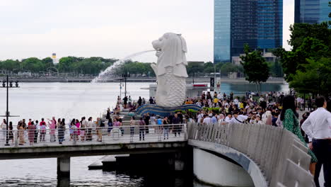 The-Singapore-Merlion-statue-with-hundreds-of-tourists-people-below-and-the-bay