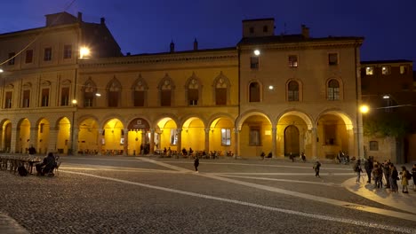 Wide-shot-of-people-standing-at-Piazza-Santo-Stefano-in-Bologna,-Italy-at-night