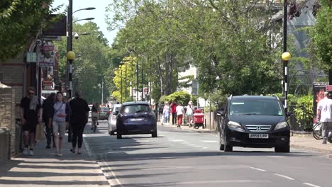 People-walk-and-drive-along-Mill-Road-in-Cambridge,-UK