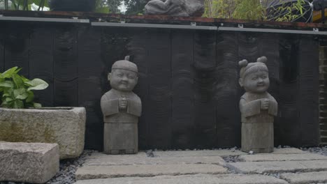 Stone-carved-statues-of-cute-Asian-boy-and-girl-in-stylized-Asian-garden