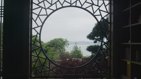 Circle-shaped-stylized-window-frame-with-the-view-on-the-forest-and-ocean-down-below-on-a-cloudy-day