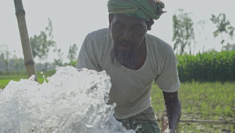 Unknown-farmer-splashing-water-into-his-face-to-wash-him-clean-while-water-pump-is-running-at-full-speed