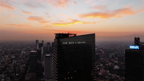 Aerial-view-around-the-Ritz-Carlton-hotel-tower,-colorful-dusk-sky-in-Mexico-city
