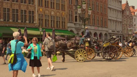 Tourists-Taking-Pictures-With-Horse-drawn-Carriage-On-The-Central-Square-Markt-In-Bruges,-Belgium