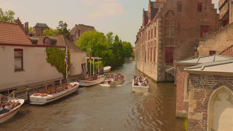 Tourists-taking-a-boat-ride-on-the-canal-in-the-city-of-Bruges,-considered-one-of-the-most-beautiful-in-Europe
