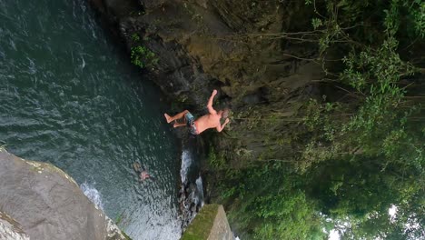 European-Adult-Male-cliff-jump-off-a-high-concrete-Platform-at-Kembar-Waterfall-of-Aling-Aling-Trek,-Bali