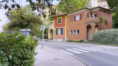 Eine-Straße-In-Rapallo-Mit-Alten-Bunten-Villen,-Einem-Roller-Oder-Moped-Und-Fußgänger,-Italien