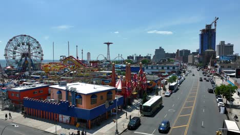Eine-Farbenfrohe-Luftaufnahme-über-Die-Straße,-Die-Sich-Dem-Vergnügungspark-Coney-Island-In-New-York-City-Nähert,-Mit-Blick-Auf-Das-Riesenrad-Und-Das-Meer-Im-Hintergrund