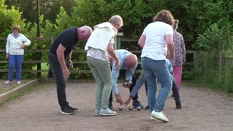 Pétanque-players-from-two-teams-picking-up-their-boulesafter-tossing-them-towards-a-cochon-trying-to-get-as-close-to-it-as-possible