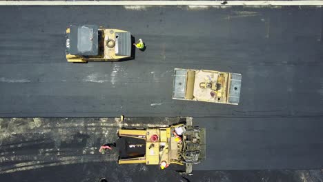 Aerial-top-down-view,-road-construction-workers,-machinery-laying-fresh-asphalt