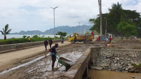 Timorese-people-cleaning-up-the-streets-of-mud-after-flooding-across-the-capital-city-of-Dili,-Timor-Leste-in-Southeast-Asia