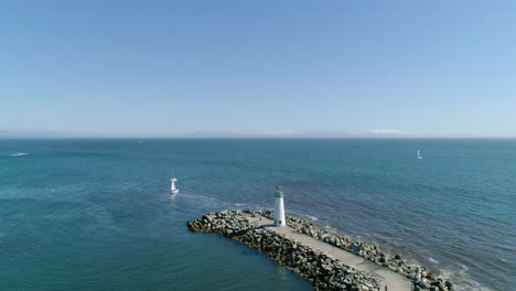 Lighthouse-on-Pier-with-Passing-Sailboats-on-the-Pacific-Coast