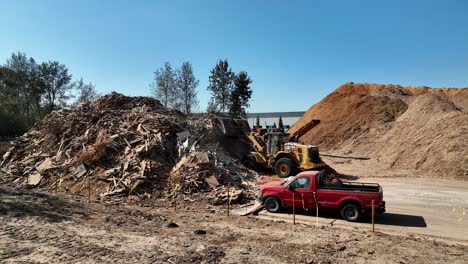 Red-Pick-Up-Truck-With-Loader-Scooping-On-The-Pile-Of-Sawmill-Waste-At-The-Recycling-Area