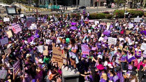 Aerial-view-around-feminists-speaking-to-a-crowd-on-International-Women's-Day,-in-Mexico