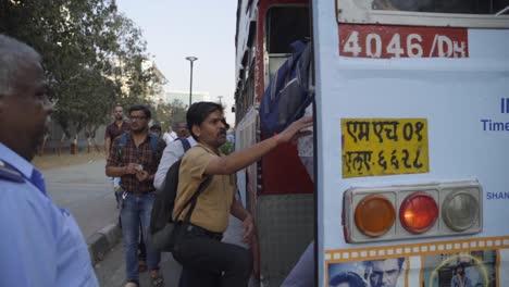 Indian-people-getting-on-a-city-bus-in-turn-guided-by-ticket-supervisor,-conductor,-Mumbai,-India