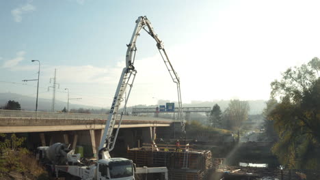 Tall-truck-mounted-concrete-pump-arm-working-at-highway-dredging-site