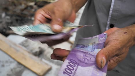 old-dirty-rupiah-paper-money-from-Indonesia-is-being-counted-in-hands,-the-Indonesian-currency-rupiahs