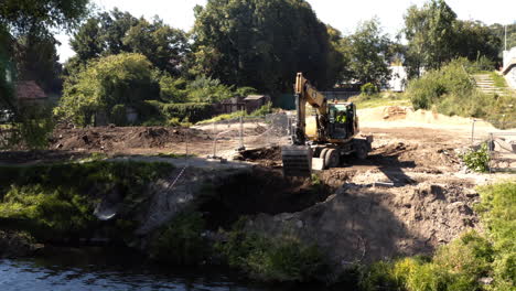Dredging-excavator-digging-hole-in-river-shore-causeway-next-to-bridge