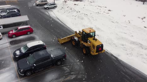 Heavy-machinery-tractor-snow-plow-clears-sidewalk-and-parking-lot-in-Canada