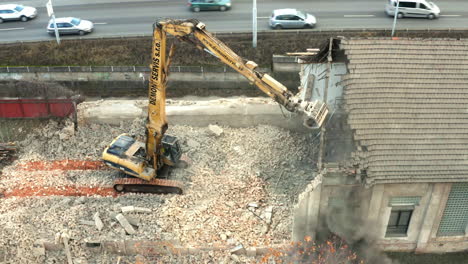 Demolition-machine-with-hydraulic-arm-destroying-house-next-to-highway