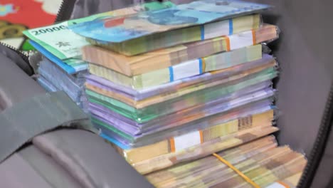 stacks-of-cash-money-in-a-moneybag-backpack,-closeup-of-different-bills-of-stacked-up-Rupiah,-Indonesian-local-currency-that-suffers-inflation