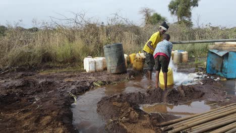 African-kids-filling-plastic-jugs-with-drinkable-water-by-borehole-well,-Kenya