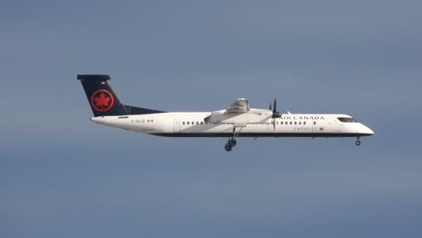 Air-Canada-Bombardier-propeller-airplane-flying-in-blue-sky,-sideways-tracking