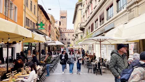 People-walking-in-Via-degli-Orefici-with-Arengo-tower-in-background-in-Bologna