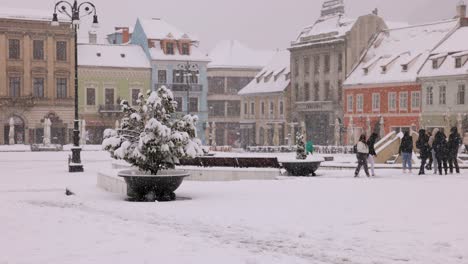 Gente-En-La-Plaza-Principal-De-La-Antigua-Ciudad-De-Brasov-En-Transilvania,-Rumania-Durante-Un-Día-Nevado