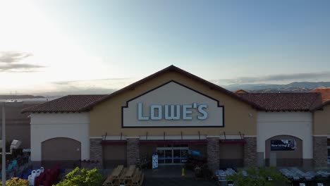 Aerial-View-Of-Front-Entrance-To-Lowe's-Home-Improvement-Store-With-Ascending-Shot-To-Reveal-Sunset-sky