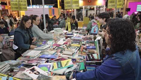 Descending-shot-of-crowded-messy-book-table-with-people-looking-for-discounted-books