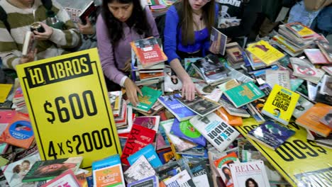 Top-down-angled-pan-above-busy-hands-grabbing-books-off-of-table