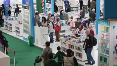 High-angle-looking-down-of-white-and-blue-bookcases-at-bookfair-as-people-walk-by