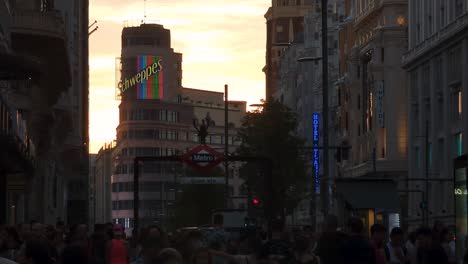 Madrid-Gran-via-street-metro-station-sign-and-Schweppes-neon-light-building-during-sunset-with-crowded-streen