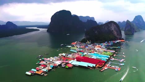 Panyee-floating-village-aerial-view-in-which-the-drone-camera-is-moving-forward-and-the-floating-houses-are-visible-in-the-water-behind-the-beautiful-and-amazing-mountains-in-the-middle-of-the-sea