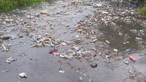 Polluted-river-filled-with-floating-plastic-and-rubbish,-environmental-disaster-of-ocean-and-rivers,-after-heavy-rain-in-capital-city-of-Dili,-Timor-Leste,-Southeast-Asia