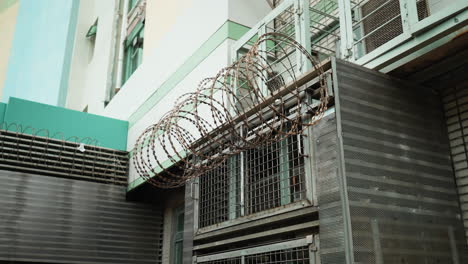 Gerollter-Stacheldraht-Hängt-An-Der-Metallöffnung-Eines-Industriegebäudes-In-Hongkong,-Asien