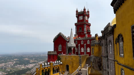 Aerial-panning-shot-of-yellow-and-red-colored-facade-of-Pena-Palace-in-Sintra,-Portugal