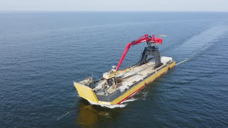 Yellow-barge-BIG-PARTNER-loaded-with-tracked-harbour-material-handling-cranes-being-towed-across-the-ocean