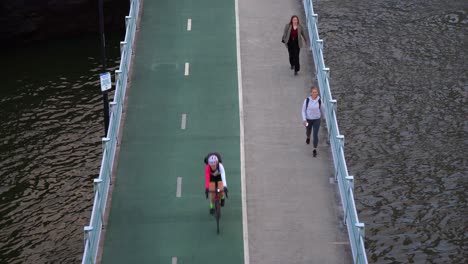 Static-shot-capturing-activity-on-bicentennial-bikeway-alongside-Brisbane-River,-cyclists-bike-riding-and-off-work-office-workers-walking-on-the-pathway-home