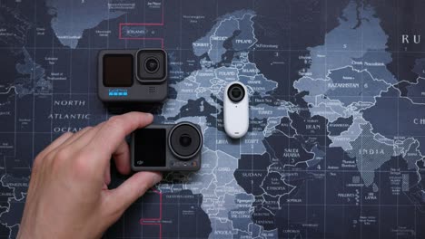 Overhead-Shot-Of-Selection-Of-Action-Cameras-Laid-Out-On-Table-As-They-Are-Taken-Away-One-By-One
